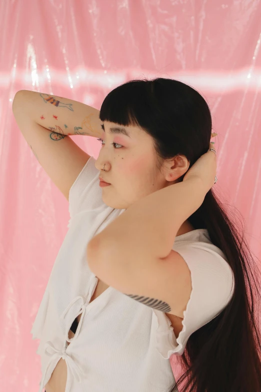 a woman with long black hair posing for a picture, an album cover, inspired by Ren Hang, unsplash, realism, pink studio lighting, arm around her neck, wearing a light shirt, tattoo