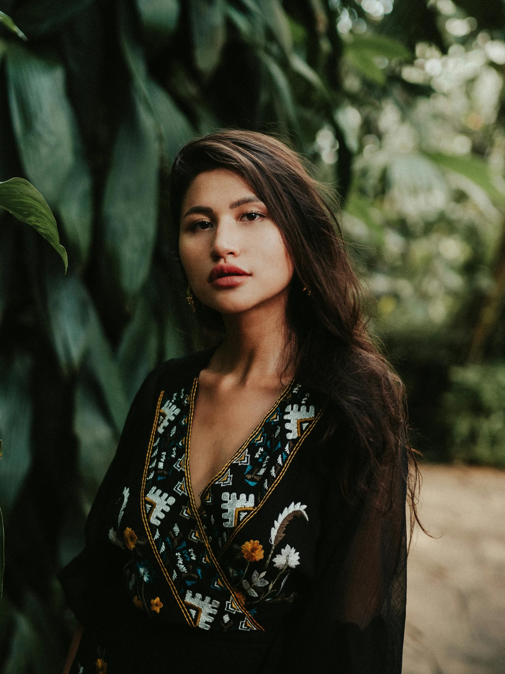 a woman standing in front of a tree, inspired by Elsa Bleda, trending on unsplash, sumatraism, wearing an elegant tribal outfit, portrait of zendaya, wearing dark silk robe, in the jungle. bloom