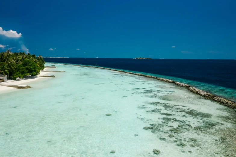 an aerial view of a beach in the middle of the ocean, hurufiyya, clear blue skies, maldives in background, walking to the right, modeled