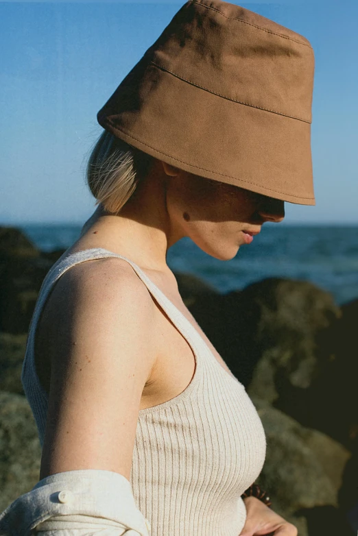 a woman in a hat looking at her cell phone, an album cover, inspired by Elsa Bleda, unsplash, renaissance, wearing tank top, coastal, wearing a brown, visor covering eyes