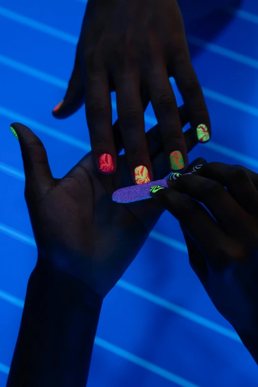 a close up of a person's hands with nail polish, a hologram, interactive art, ( ( dark skin ) ), black light, ap