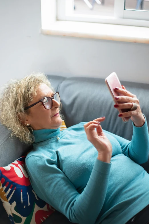 a woman laying on a couch using a cell phone, a photo, going gray, square, swedish, 5 5 yo