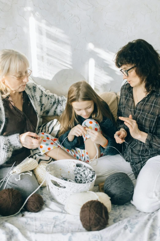 a group of women sitting on top of a bed, a cross stitch, pexels contest winner, families playing, yarn ball, profile image, advanced technology