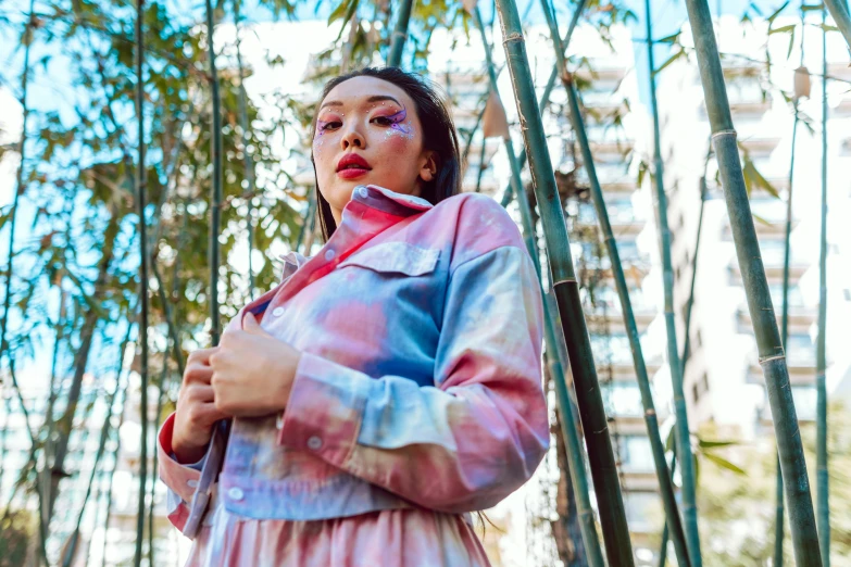 a woman standing in front of a bamboo tree, an album cover, trending on pexels, graffiti, pastel clothing, portrait sophie mudd, red and blue garments, wearing a fancy jacket