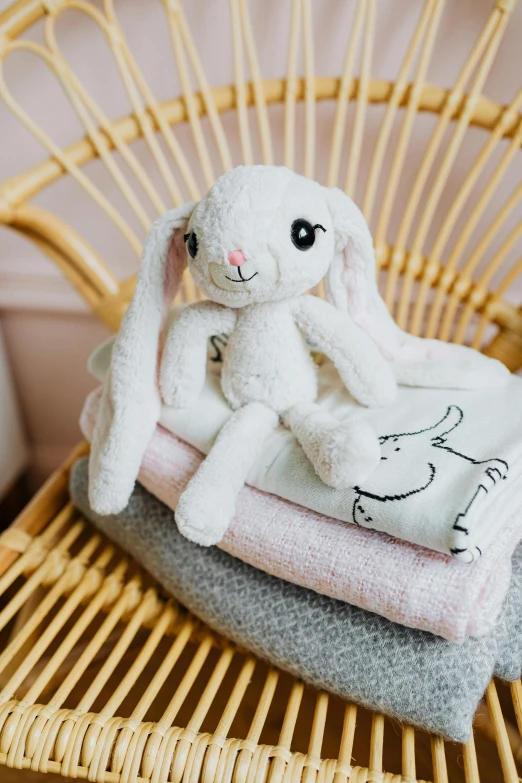 a stuffed animal sitting on top of a stack of towels, jellycat, lots de details, rabbit, white and pink