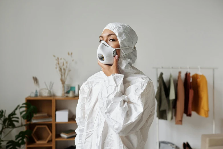 a woman in a protective suit talking on a cell phone, trending on pexels, hyperrealism, white clothing, avatar image, dust mask, at home