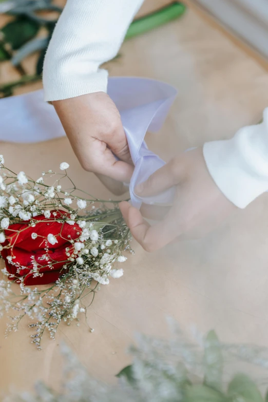 a close up of a person putting flowers on a table, inspired by Cui Bai, romanticism, formal wear, ribbon, plain, robe