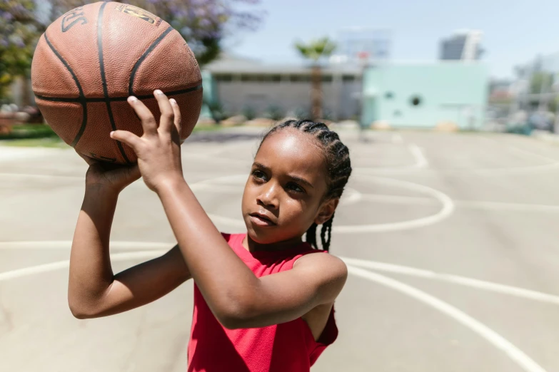 a young girl holding a basketball on a basketball court, by Greg Spalenka, pexels contest winner, light-brown skin, left eye red stripe, frontal shot, childish