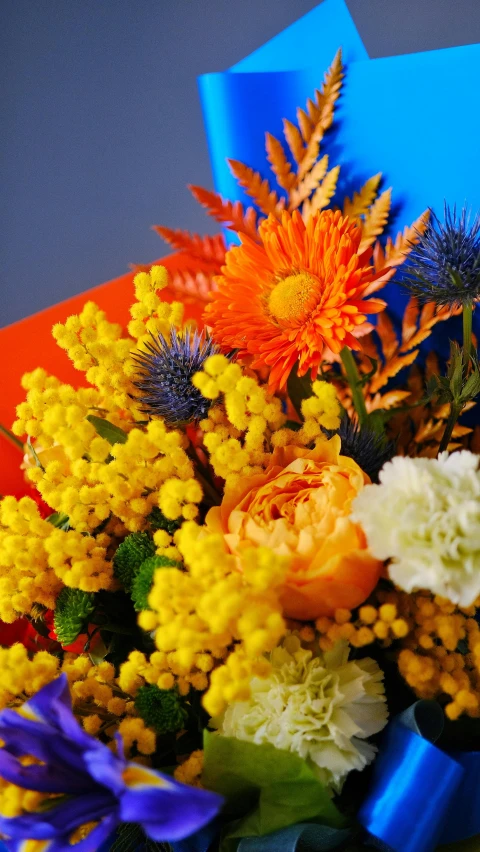 a bouquet of flowers sitting on top of a table, by Carey Morris, shutterstock contest winner, yellow and orange color scheme, blue, medium close up, festive