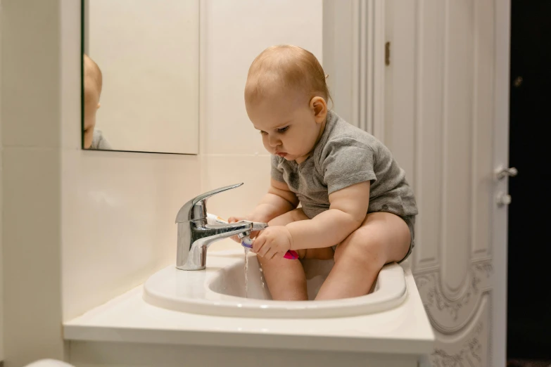 a baby sitting on top of a sink in a bathroom, inspired by Myles Birket Foster, pexels contest winner, 3 4 5 3 1, highly polished, blocked drains, profile pic