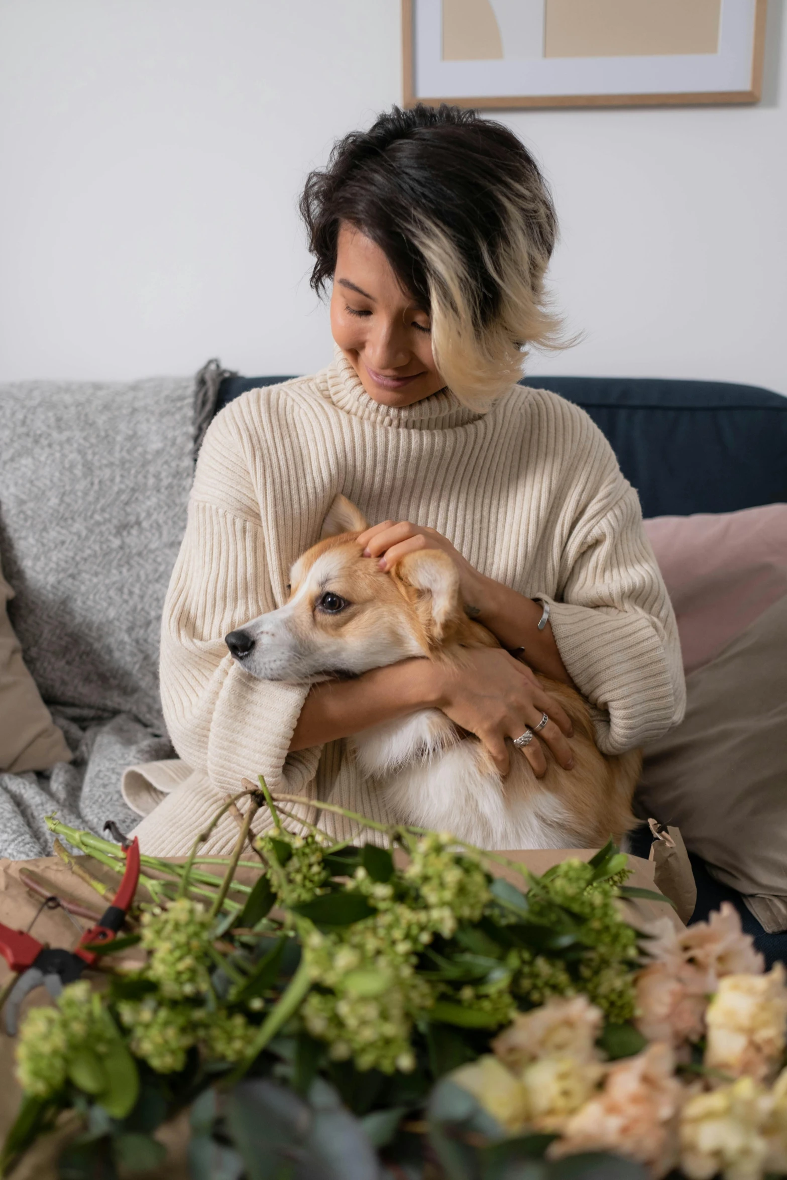 a woman sitting on a couch holding a dog, pexels contest winner, romanticism, with flowers and plants, wearing casual sweater, cornucopia, australian