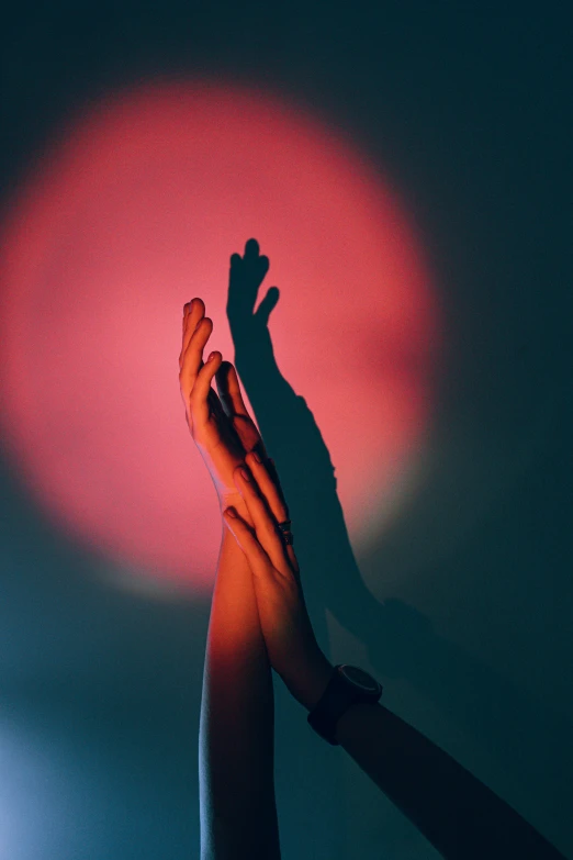 a person holding their hands up in the air, an album cover, inspired by Elsa Bleda, aestheticism, gradient light red, shadow play, colored gel lighting, instagram photo
