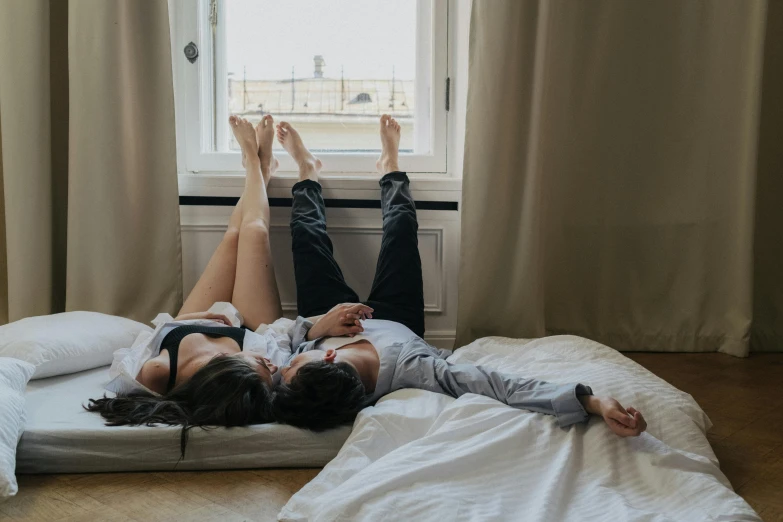 a couple of people laying on top of a bed, by Emma Andijewska, pexels contest winner, near a window, lower quality, romantic lead, high quality upload