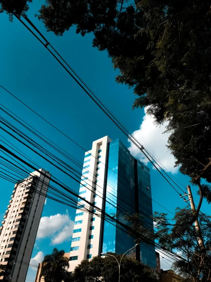a tall building sitting in the middle of a city, by Sven Erixson, electrical wires, brazilian, high-quality photo, light blue sky