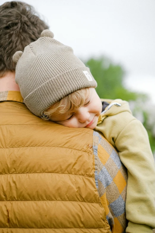 a man carrying a child on his back, pexels, beanie, movie still of a tired, wearing jacket, tan