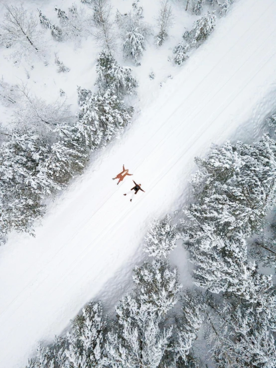 a couple of people riding skis down a snow covered slope, by Emma Andijewska, pexels contest winner, birds eye photograph, lying down, thumbnail, multiple stories