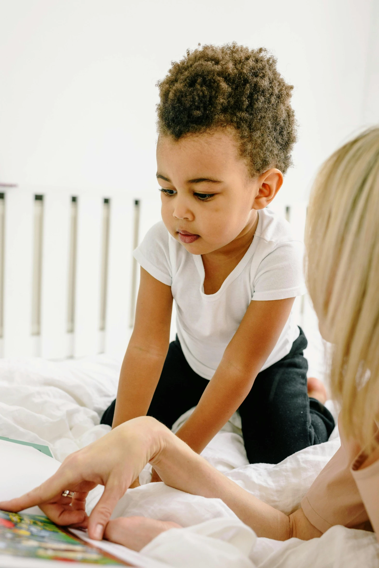 a woman and a child reading a book on a bed, diverse ages, toddler, thumbnail, grey