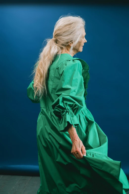 a woman in a green dress is walking, an album cover, inspired by Ulrika Pasch, trending on pexels, renaissance, older woman, comme des garcon campaign, studio portrait, greens and blues