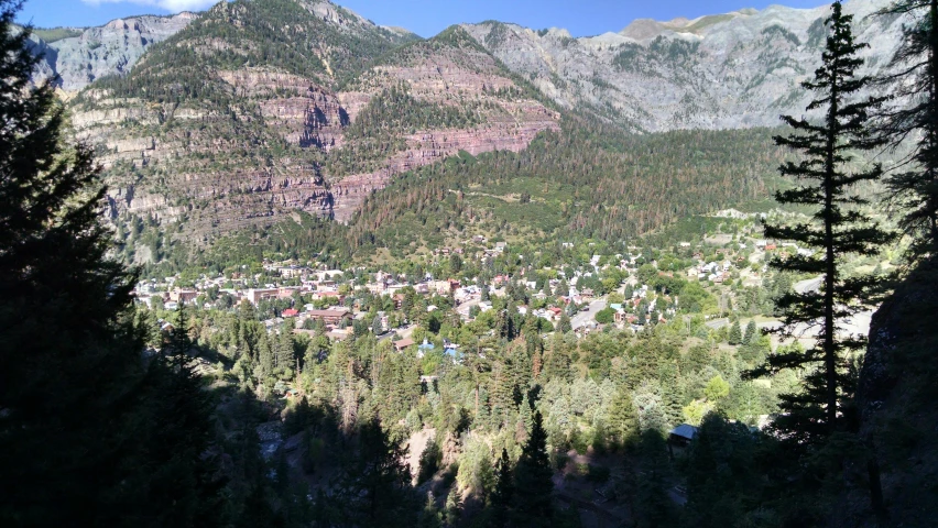 a view of a small town in the mountains, rocky mountains, with dark trees in foreground, geology, no crop