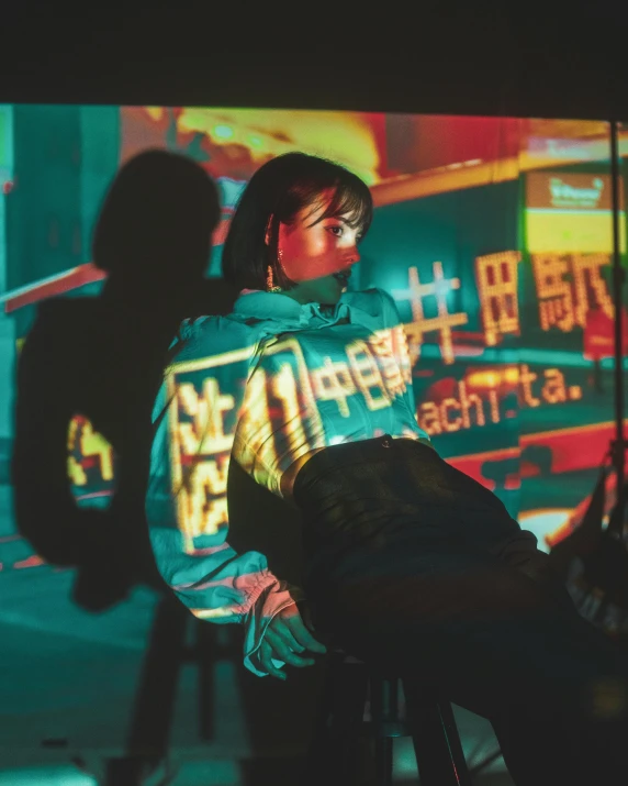 a woman sitting on top of a chair in front of a tv, inspired by Liam Wong, unsplash contest winner, holography, she wears a jacket, glowing street signs, chinese woman, reflective material