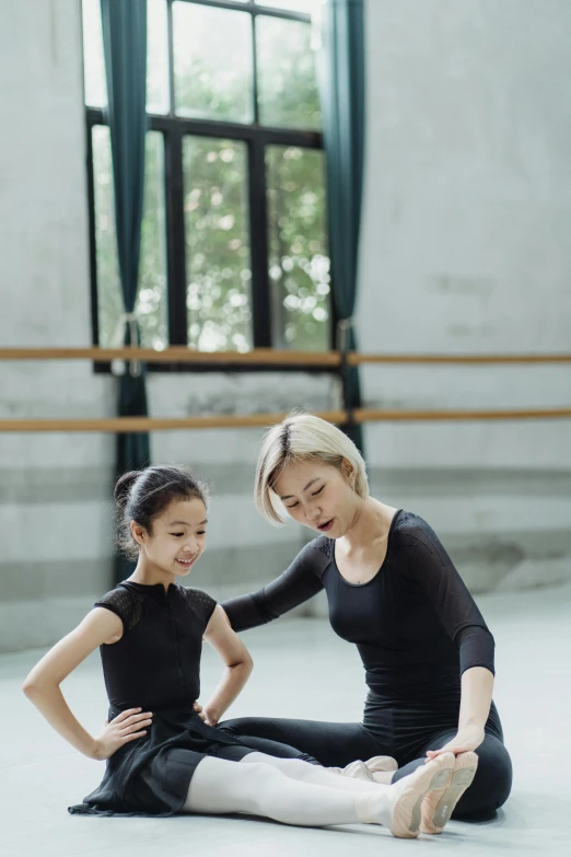 a woman sitting on the floor next to a little girl, inspired by Fei Danxu, pexels contest winner, arabesque, standing sideways, in a workshop, teaching, beijing