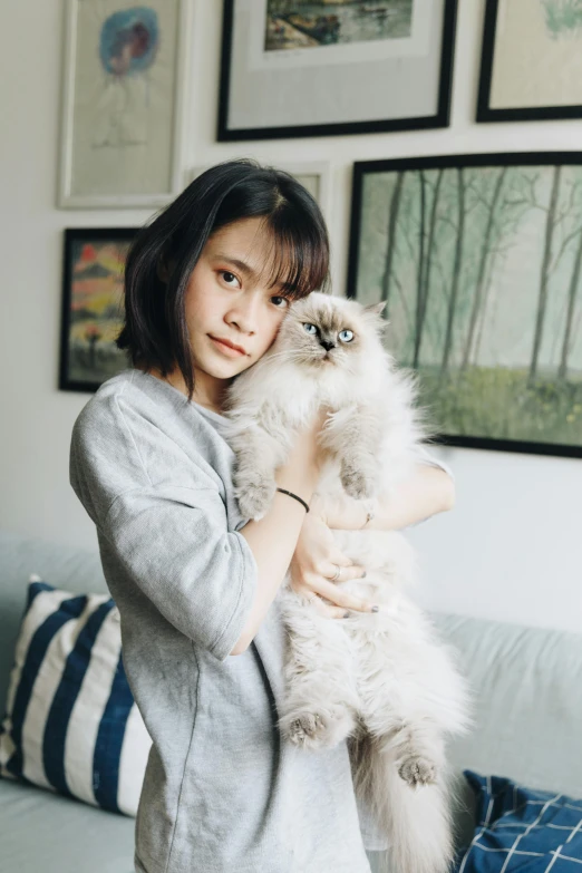 a woman holding a cat in her arms, a picture, by Tan Ting-pho, pexels contest winner, visual art, fluffy bangs, square, handsome girl, at home