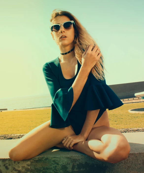 a woman sitting on top of a stone wall, a polaroid photo, inspired by Elsa Bleda, unsplash, fashion model in sunglasses, wearing leather swim suite, trending on imagestation, lawns