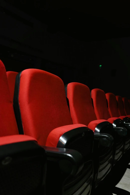 a row of red chairs in a dark room, imdb, ( ( theatrical ) ), multiple stories, [ theatrical ]