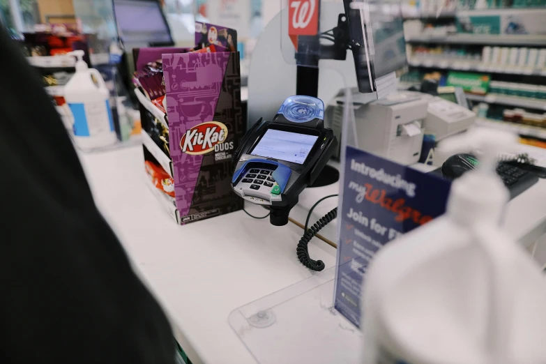 a phone sitting on top of a counter in a store, convenience store, candy treatments, aussie baristas, ko-fi