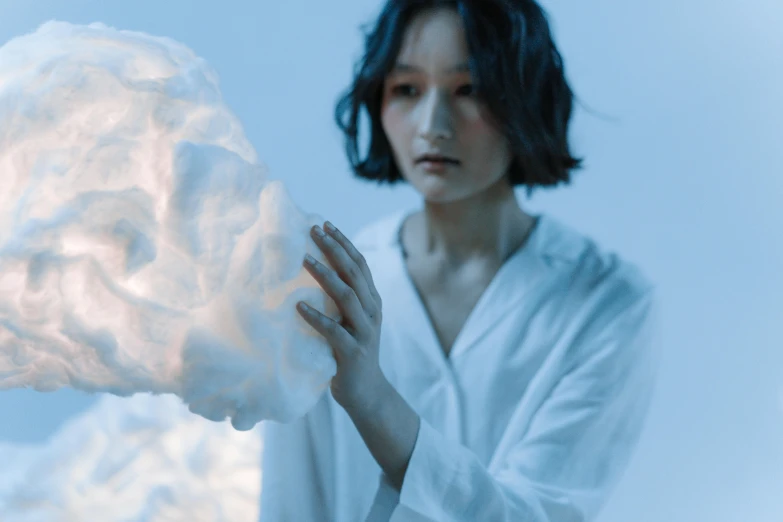 a woman holding a cloud in front of her face, a marble sculpture, by Ayami Kojima, unsplash, conceptual art, japan. volumetric lighting, singularity sculpted �ー etsy, cotton cloud mage robes, woman and robot