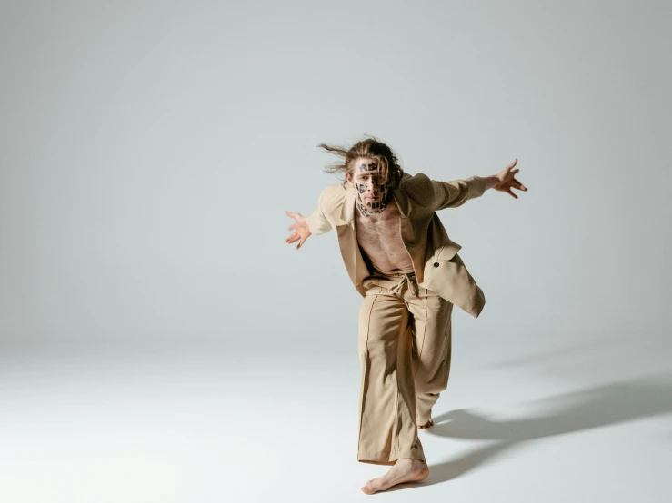 a man that is standing in the air, an album cover, trending on pexels, antipodeans, tan suit, contemporary dance poses, heilung, captures emotion and movement