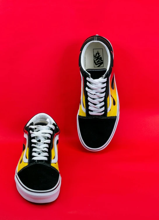 a pair of black and yellow sneakers on a red background, by Bernie D’Andrea, tumblr, snake van, red flames in background, left eye stripe, gradient yellow