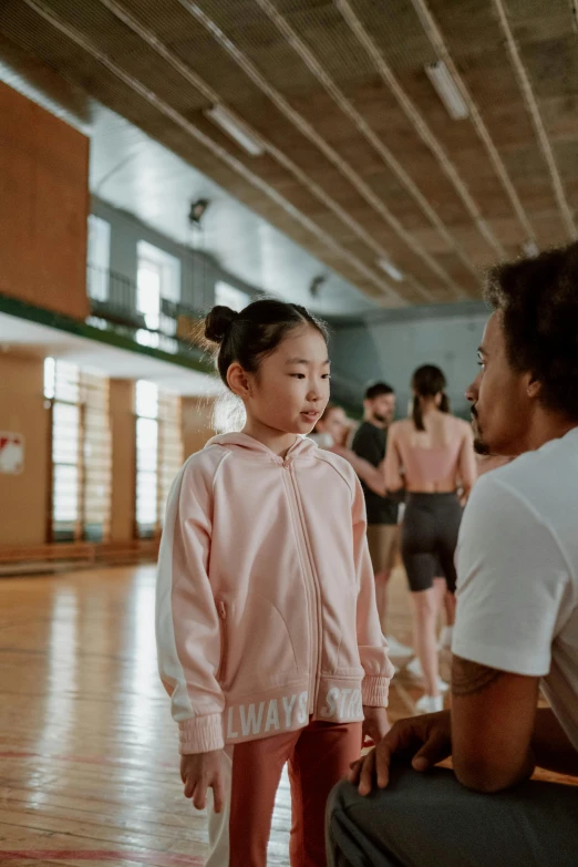 a little girl standing next to a man in a gym, by Fei Danxu, pexels contest winner, wearing a track suit, dance scene, ( ( theatrical ) ), innocent look