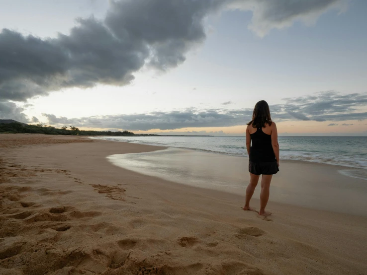 a woman standing on top of a sandy beach, by Jessie Algie, unsplash contest winner, maui, calm evening, walking to the right, australian beach