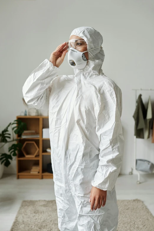 a man in a protective suit talking on a cell phone, a picture, shutterstock, renaissance, ripped up white garment, sustainable materials, at home, she is wearing a wet coat