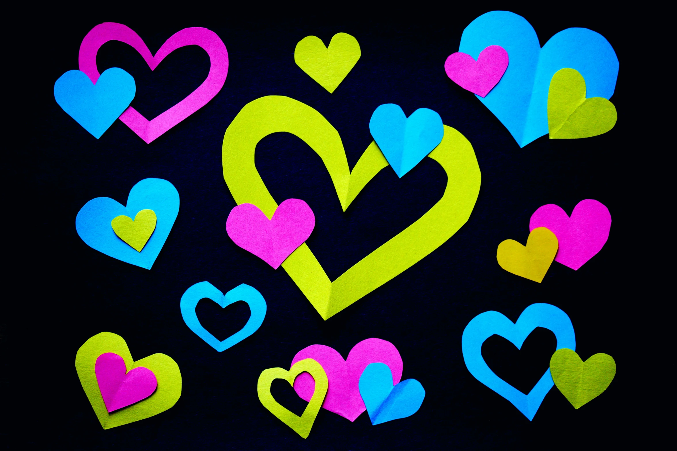 a bunch of paper hearts on a black background, by Julia Pishtar, pexels, graffiti, dayglo pink blue, 15081959 21121991 01012000 4k, romantic lead, family photo