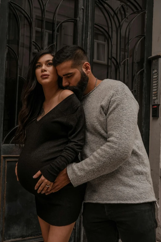 a man and a woman standing next to each other, a colorized photo, pexels contest winner, maternity feeling, middle eastern, black and grey, handsome girl