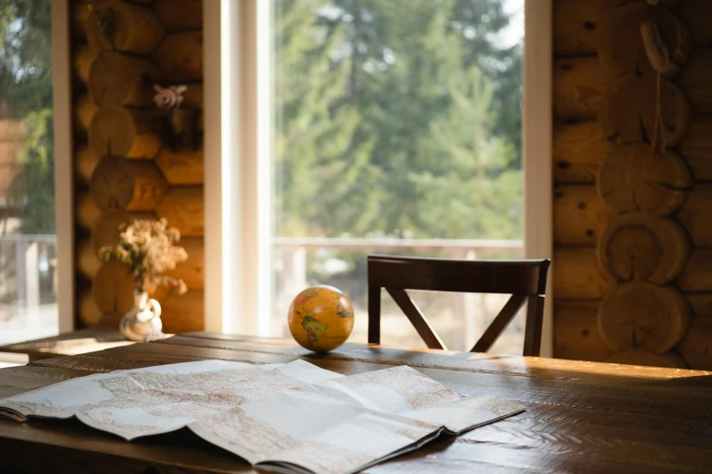 an open book sitting on top of a wooden table, in a cabin, map, airbnb, kitchen table