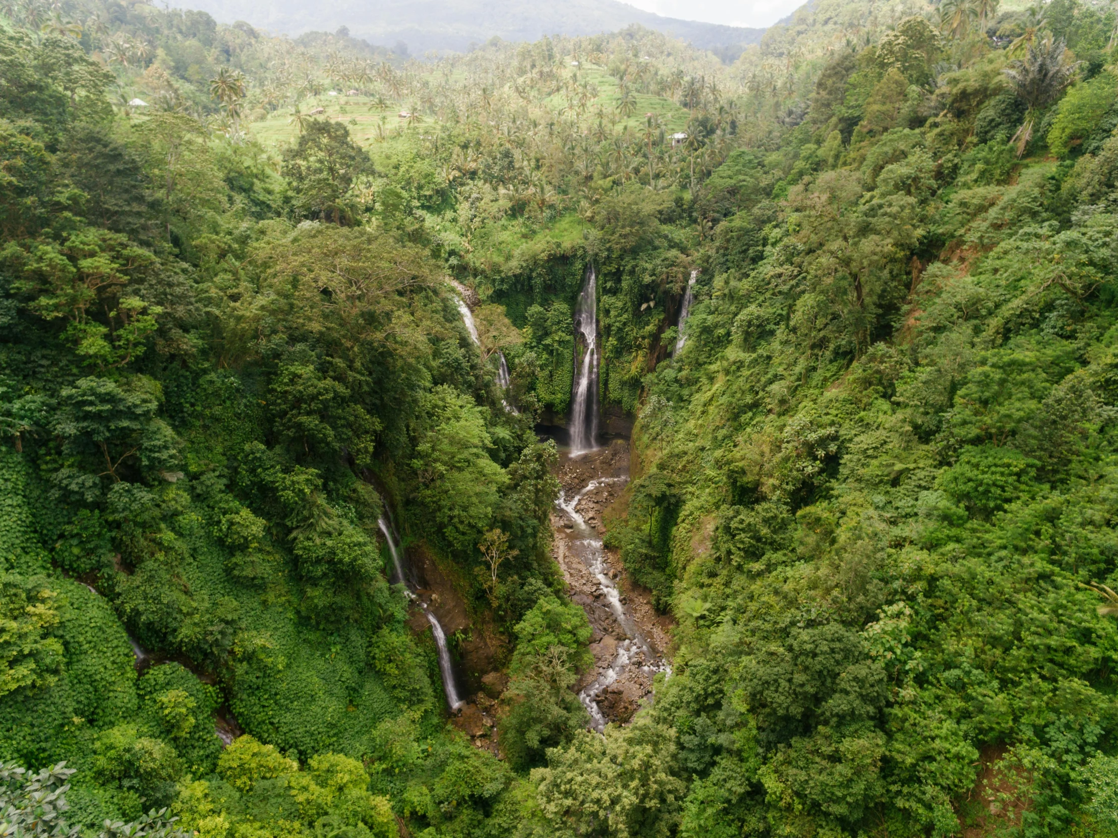 a waterfall in the middle of a lush green forest, hurufiyya, wide overhead shot, tawa trees, conde nast traveler photo, multiple stories