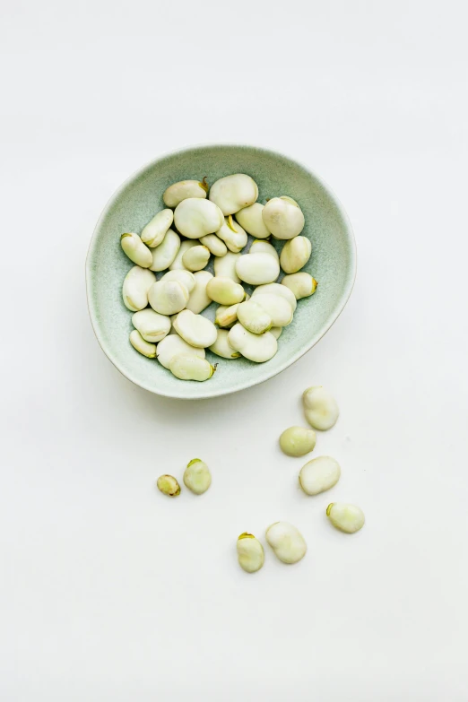 a bowl of beans on a white surface, by Nicolette Macnamara, renaissance, pale green glow, sza, stones, flat