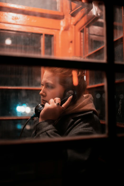 a woman talking on a telephone in a phone booth, a photo, inspired by Elsa Bleda, pexels, realism, movie still from bladerunner, redhead woman, investigation, square