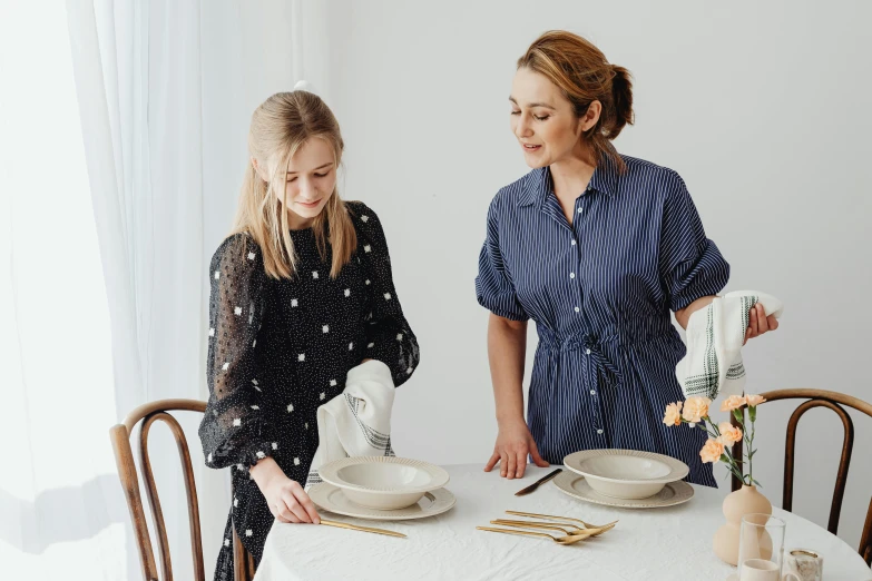 a woman standing next to a little girl at a table, by Alice Mason, pexels contest winner, wearing a linen shirt, gal gadot china plate, polka dot, white bg