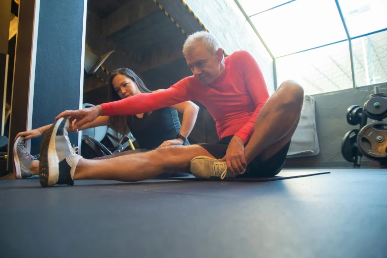 a man and woman sitting on the floor in a gym, by Julian Allen, pexels contest winner, renaissance, older male, pixeled stretching, thigh focus, thumbnail