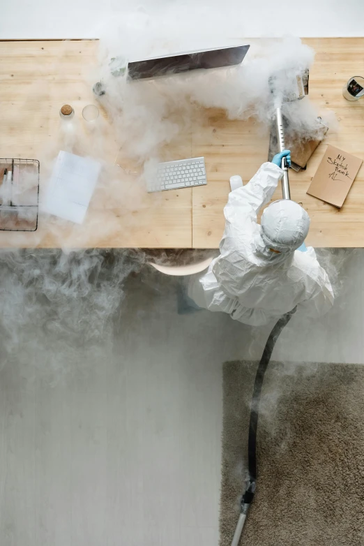 a person spraying something with a spray gun, inspired by Rube Goldberg, pexels contest winner, dry ice, on desk, dwell, surgeon