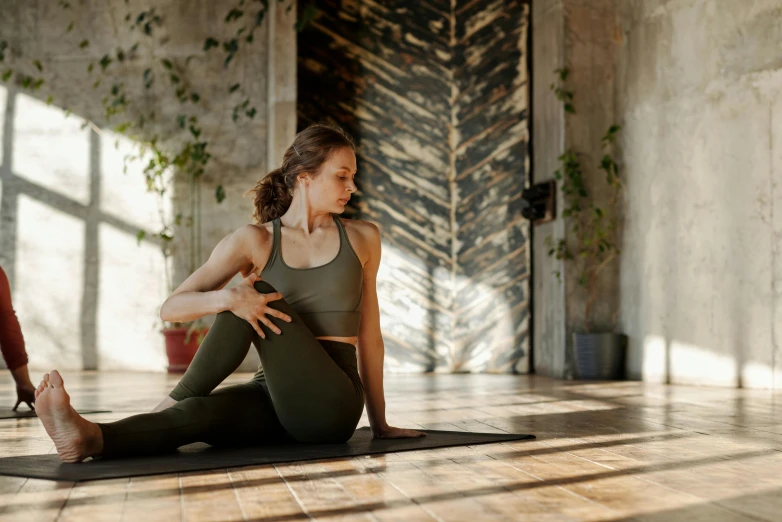 a woman sitting on top of a yoga mat, by Emma Andijewska, pexels contest winner, renaissance, forward facing pose, natural light in room, knees upturned, brown