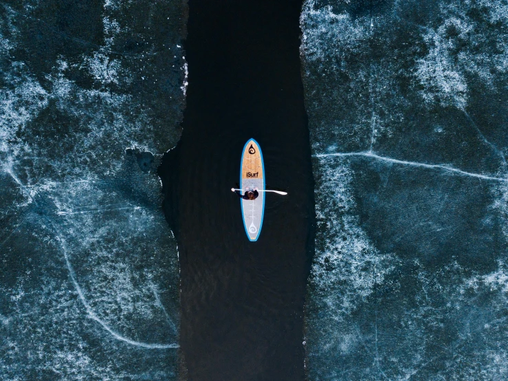 a person riding a surfboard on top of a body of water, by Adam Marczyński, pexels contest winner, minimalism, blue river in the middle, canoe, icy lake setting, on black background