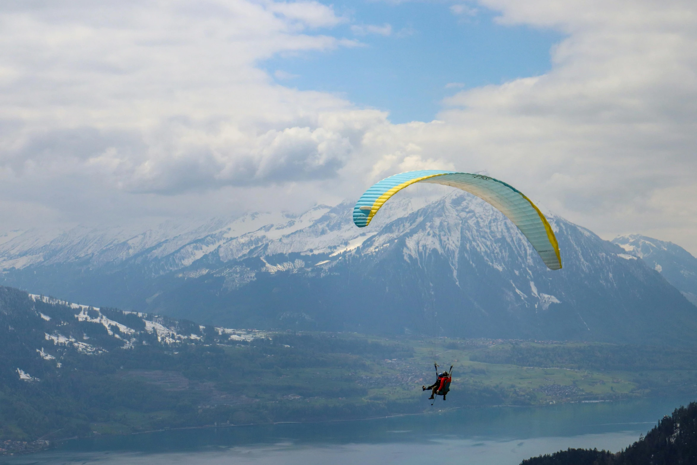 a paraglider flying over a lake with mountains in the background, by Niko Henrichon, pexels contest winner, canopy, geiger, 9 9 designs, over a chalk cliff