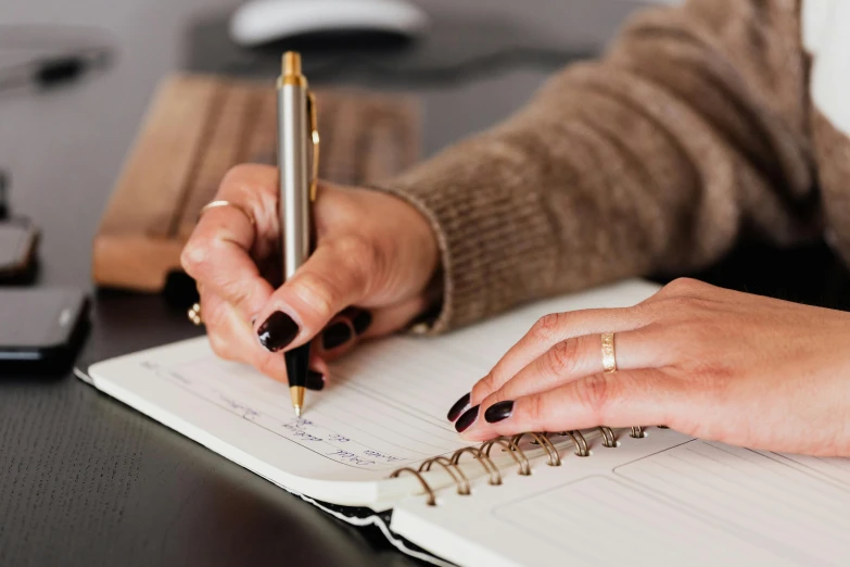 a close up of a person writing on a notebook, by Julia Pishtar, trending on pexels, te pae, elegantly dressed, curated collections, a high angle shot