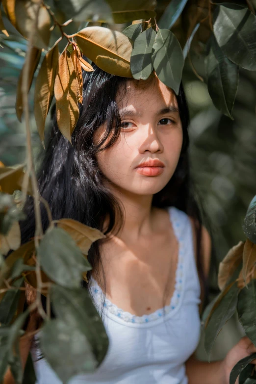 a woman standing in a tree with leaves on her head, a picture, inspired by Ruth Jên, pexels contest winner, young cute wan asian face, medium portrait top light, looking serious, big leaf bra