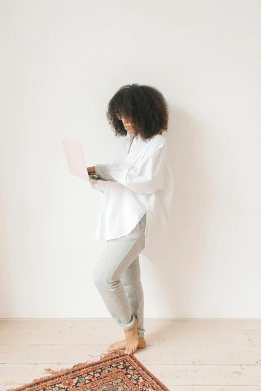 a woman standing in front of a rug reading a book, pexels contest winner, minimalism, wearing a white button up shirt, afro tech, full body angle, holding a clipboard